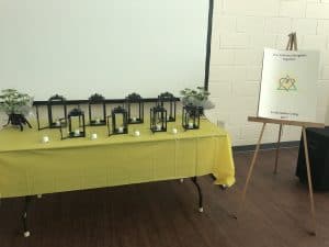 Lanterns and tealights on an elegant table with welcome sign on an easel.