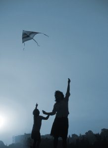 Silhouette of woman and child flying a kite