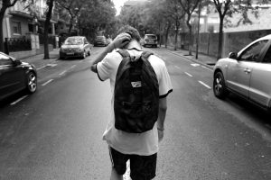 Distraught teenage boy with backpack in the middle of a street